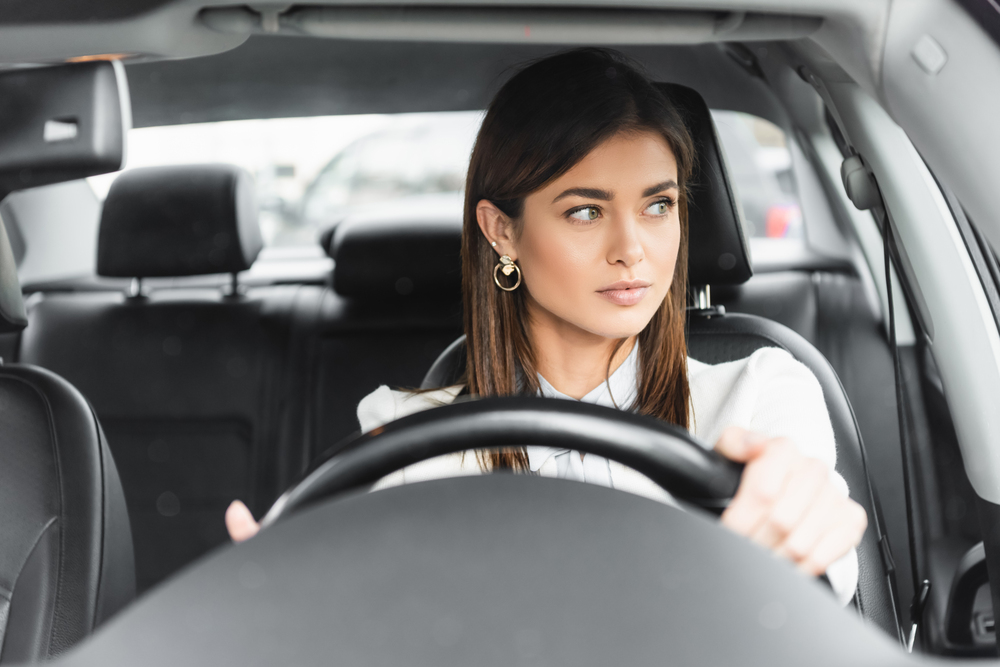 While driving, a woman ponders why the wind noise is worse than before.