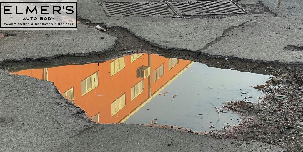 A pothole in the street that is reflecting a building on the water's surface.